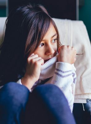 Anxious girl sitting at school desk feeling nervous about class